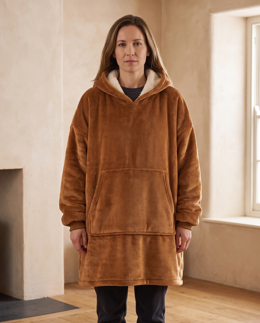 Woman wearing the Alba sherpa-lined hooded blanket in cognac, the cream lining visible in the hood, front view