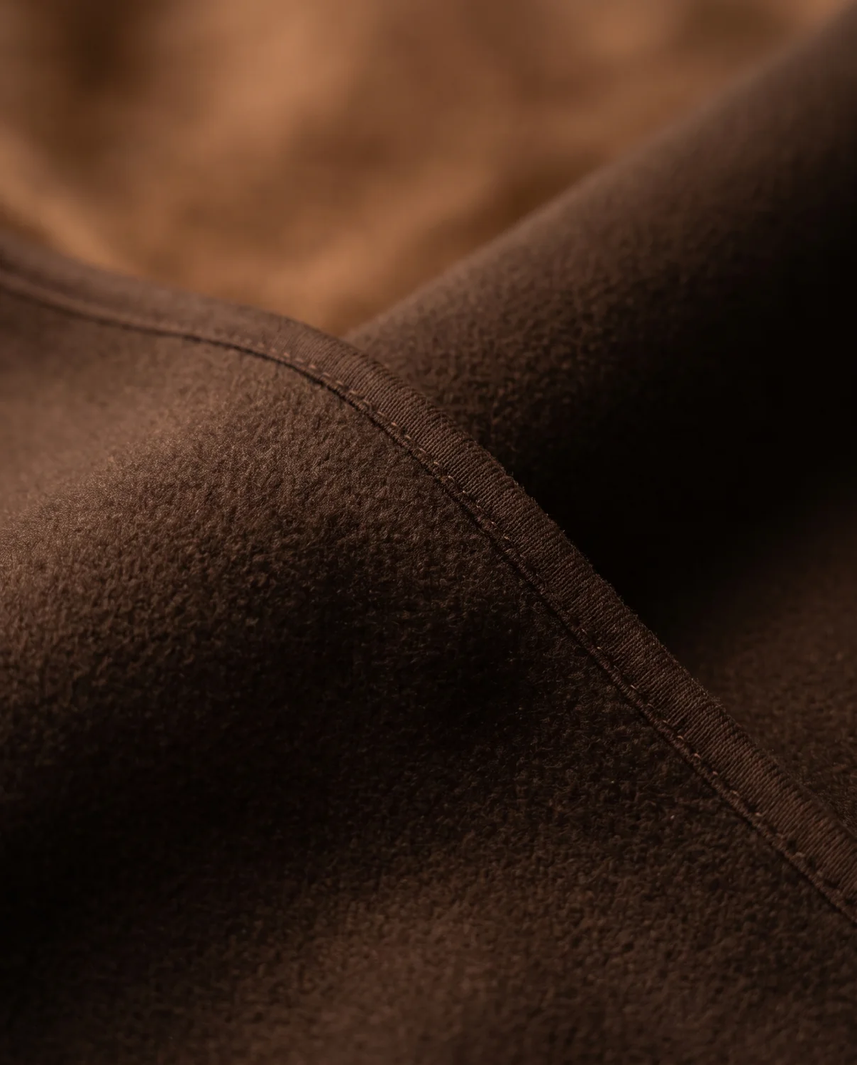 Close-up of the Otis hooded blanket in espresso showing the smooth matte fleece exterior and plush lined hood